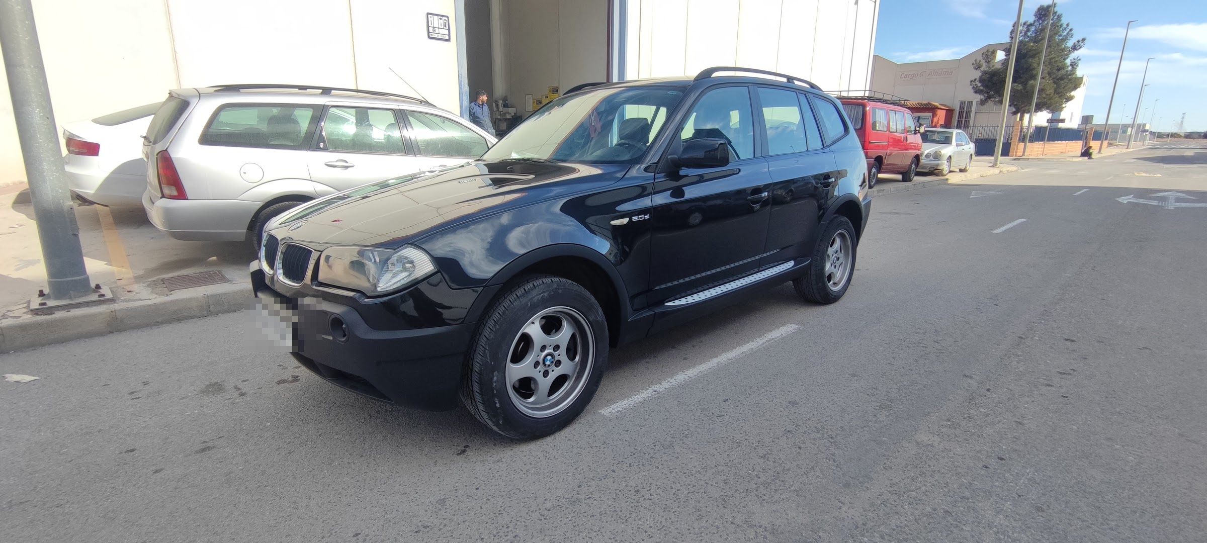 Un coche a la puerta del Taller Redauto, con la nave abierta, en el polígono Las Salinas de Alhama de Murcia
